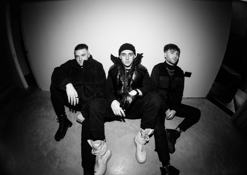 Black & White image of three men sat on the groundx
